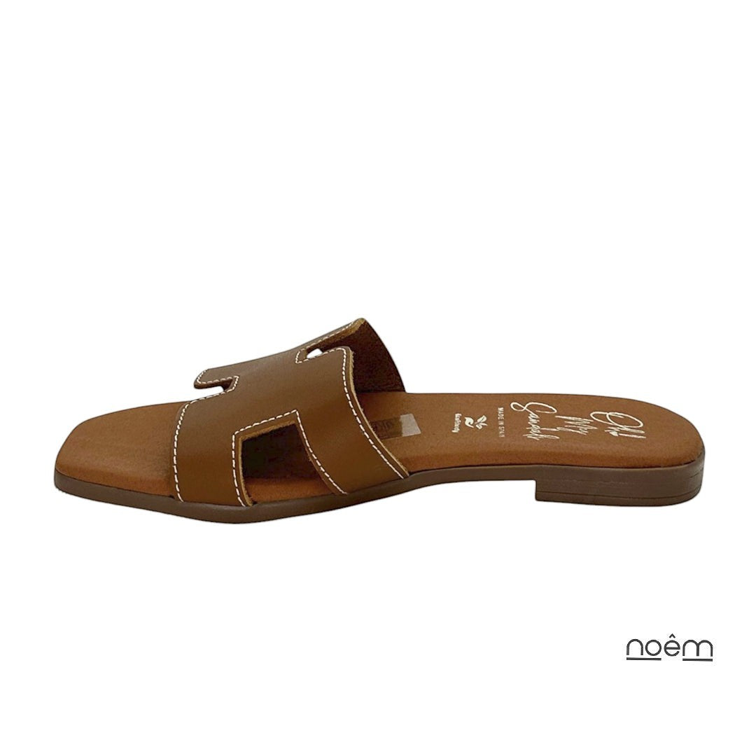 Sandalia plana de piel camel con pala troquelada y costuras blancas. Diseño minimalista de Noêm & Seque.