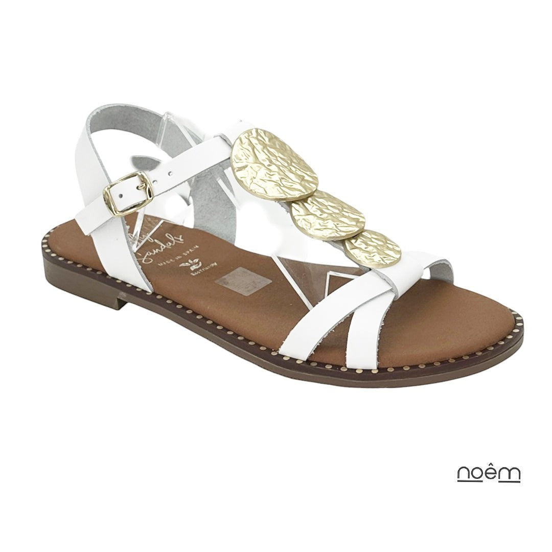 Sandalia plana blanca de piel con tiras cruzadas y detalle de discos dorados texturizados. Cierre ajustable al tobillo. Marca Oh My Sandals.