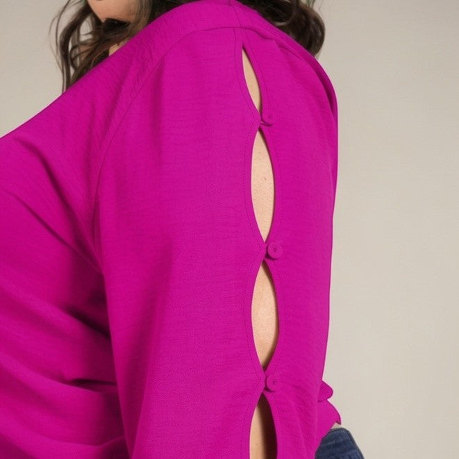 Noêm & Seque fuchsia pink blouse with buttoned side cut-outs on the sleeve. Long sleeves, crew neck.