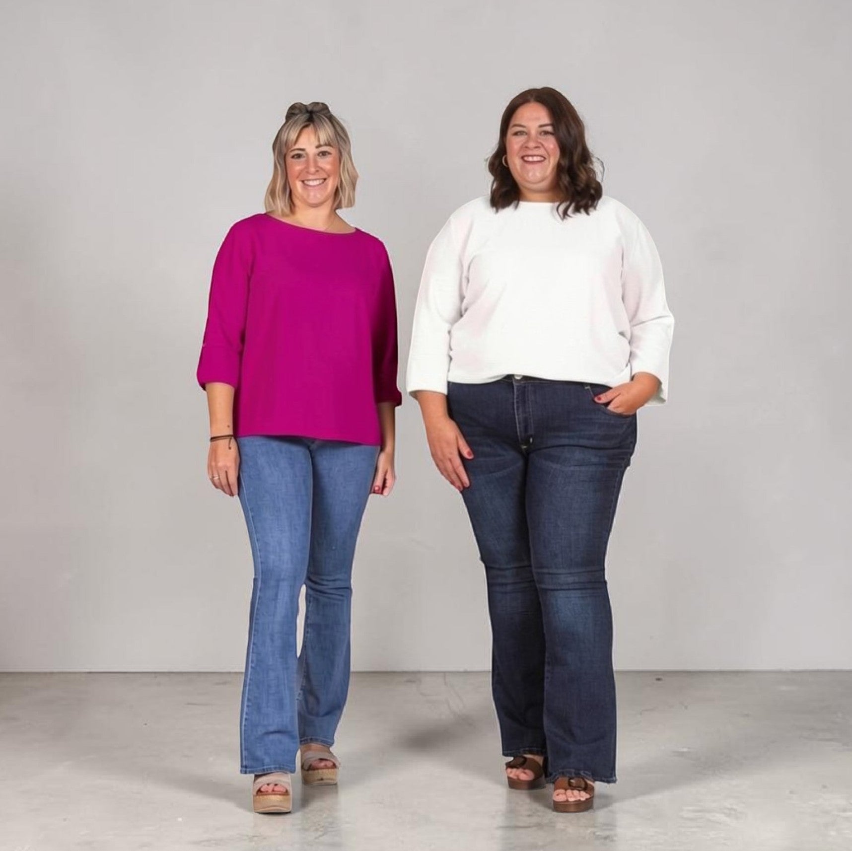 Noêm & Seque women in magenta and white long-sleeved tops with flared jeans. The magenta top has a boat neck and cuffed sleeves.